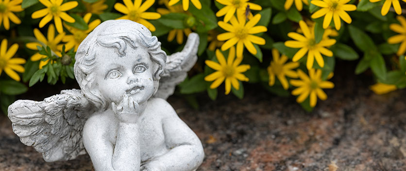 Angel on a tombstone with yellow flowers
