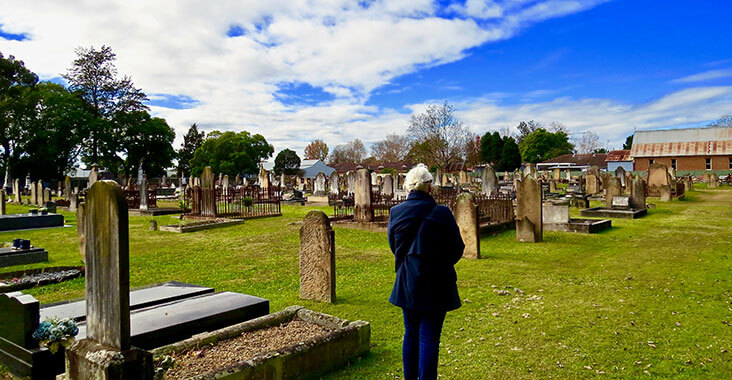 Woman standing in graveyard looking at headstones