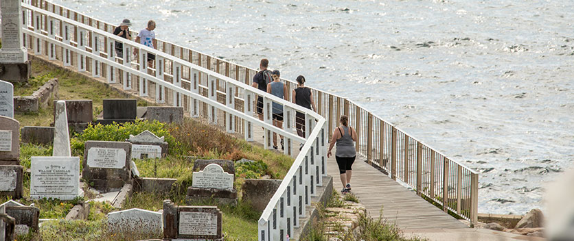 People walking beside Waverley Cemetery next to the ocean