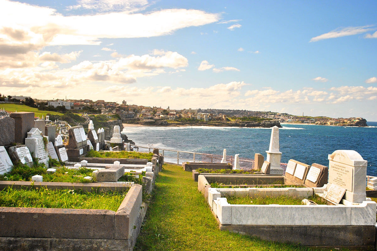 Multiple headstones in a cemetery in NSW overlooking ocean views.