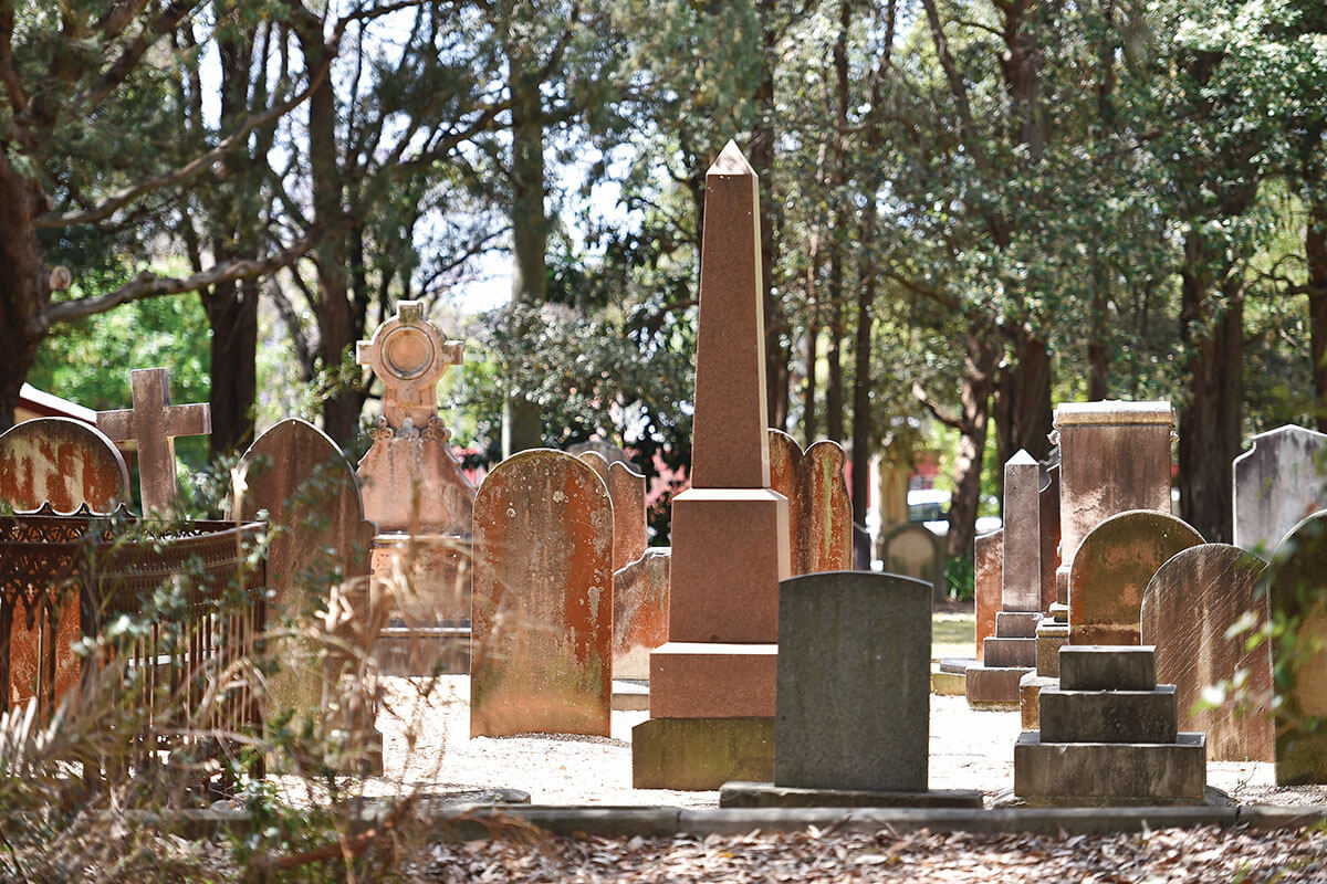 Orange coloured headstones in cemetery with natural bush setting.